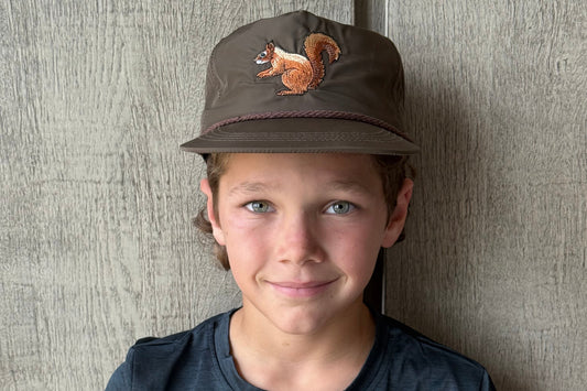 Person wearing a cap with a squirrel on it, lying on a textured surface