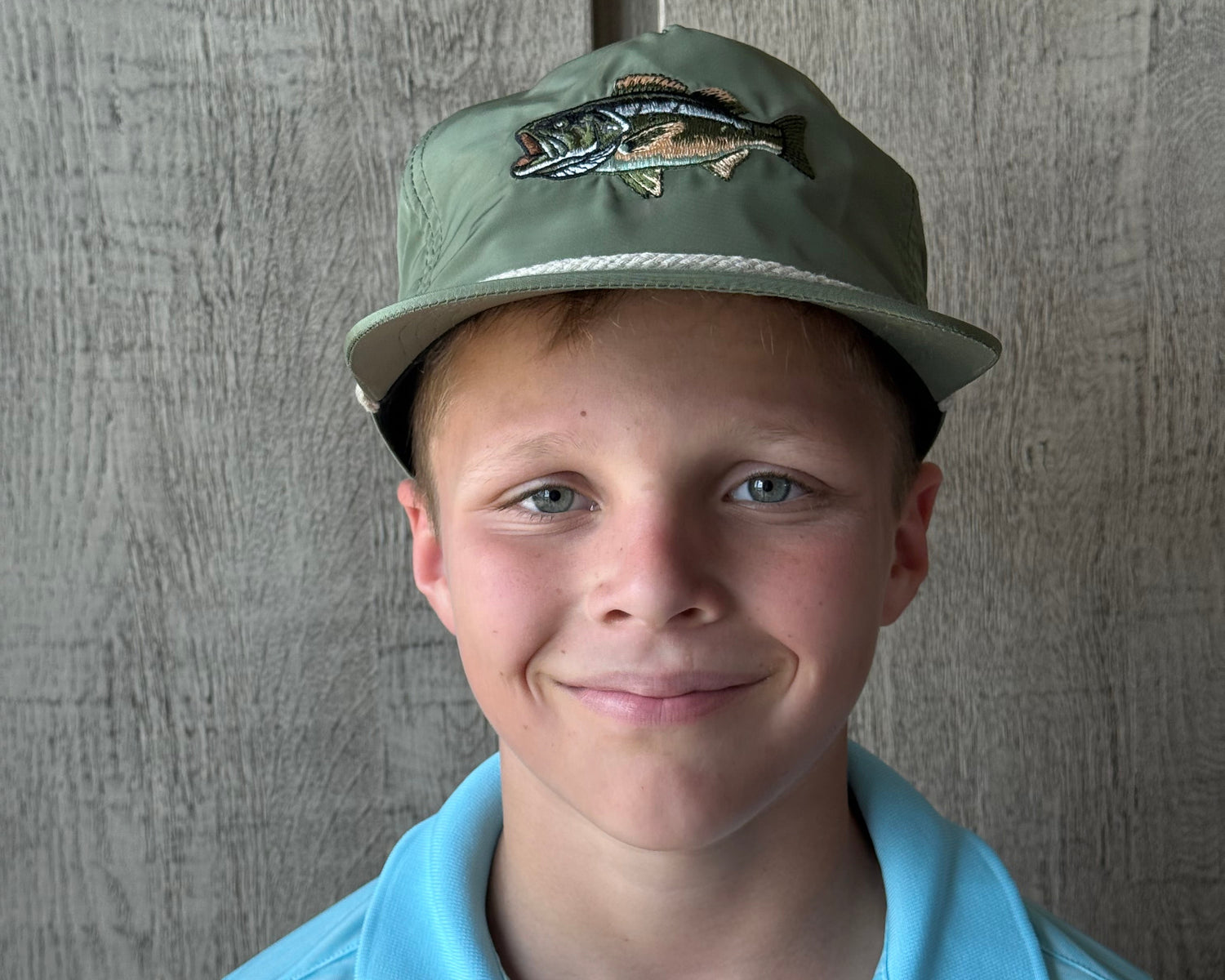 Person wearing a green and beige large mouth bass cap vintage rope hat